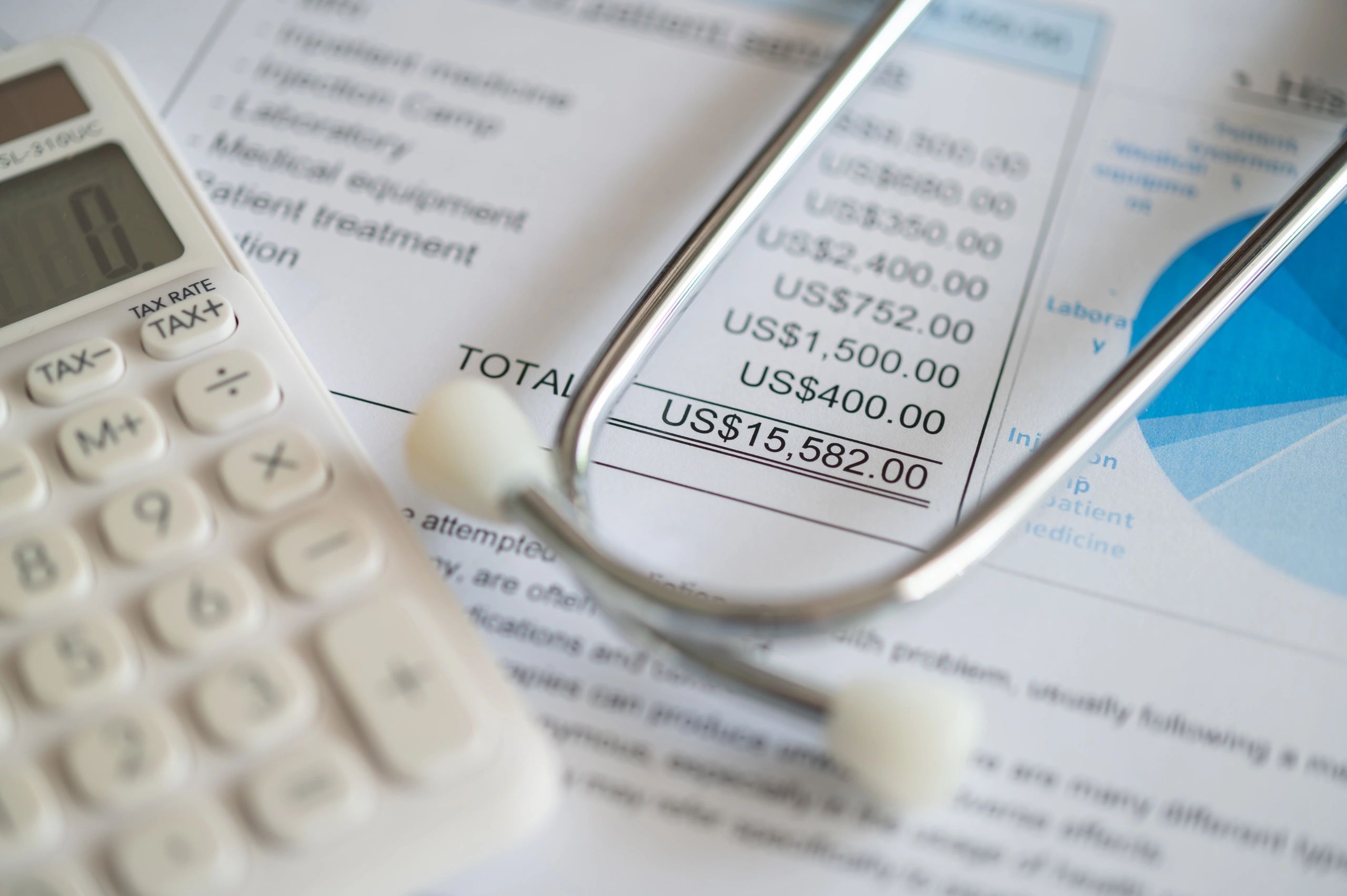 medical billing document and dollar banknote, calculator, stathoscope.